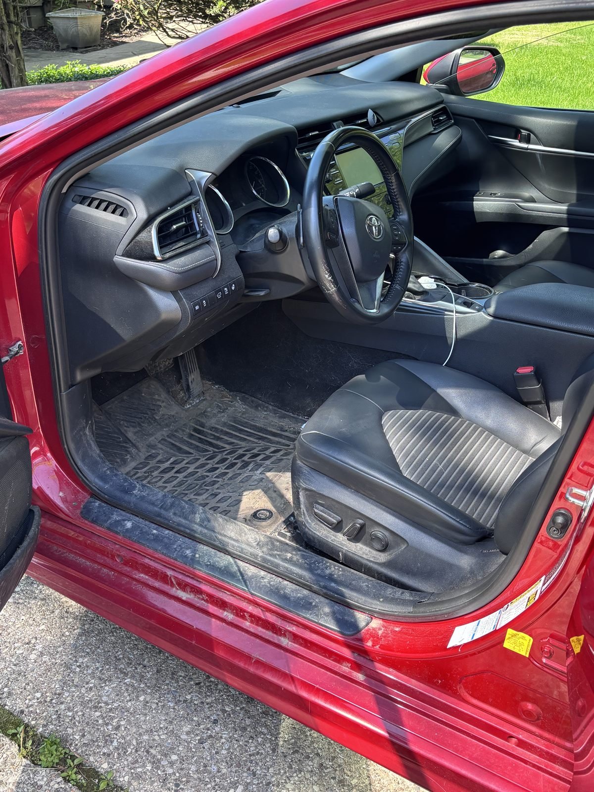 Before detailing: dusty driver's seat, door sill and floor mat of a red sedan