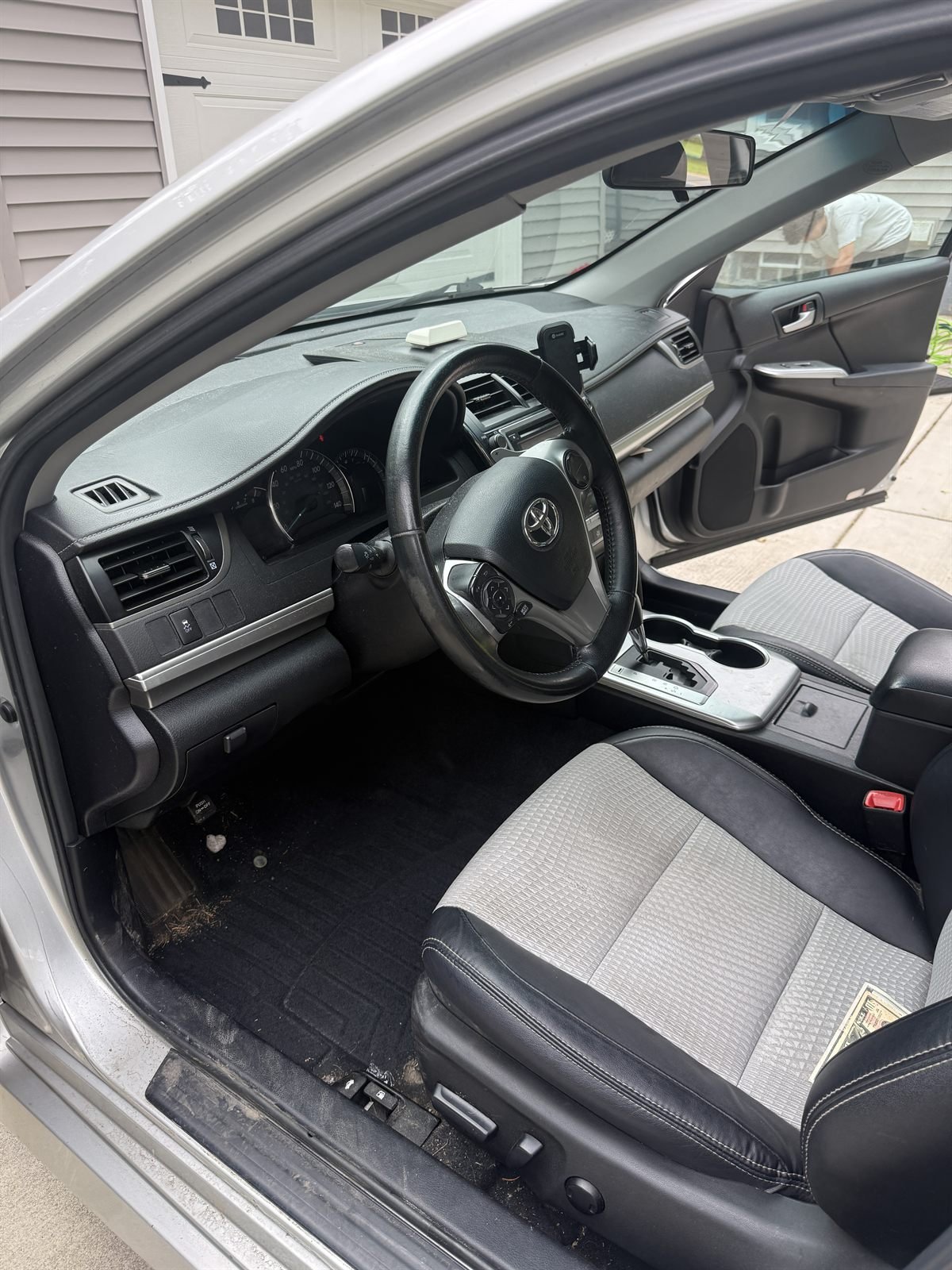 Before detailing: dusty driver-side interior of a silver sedan