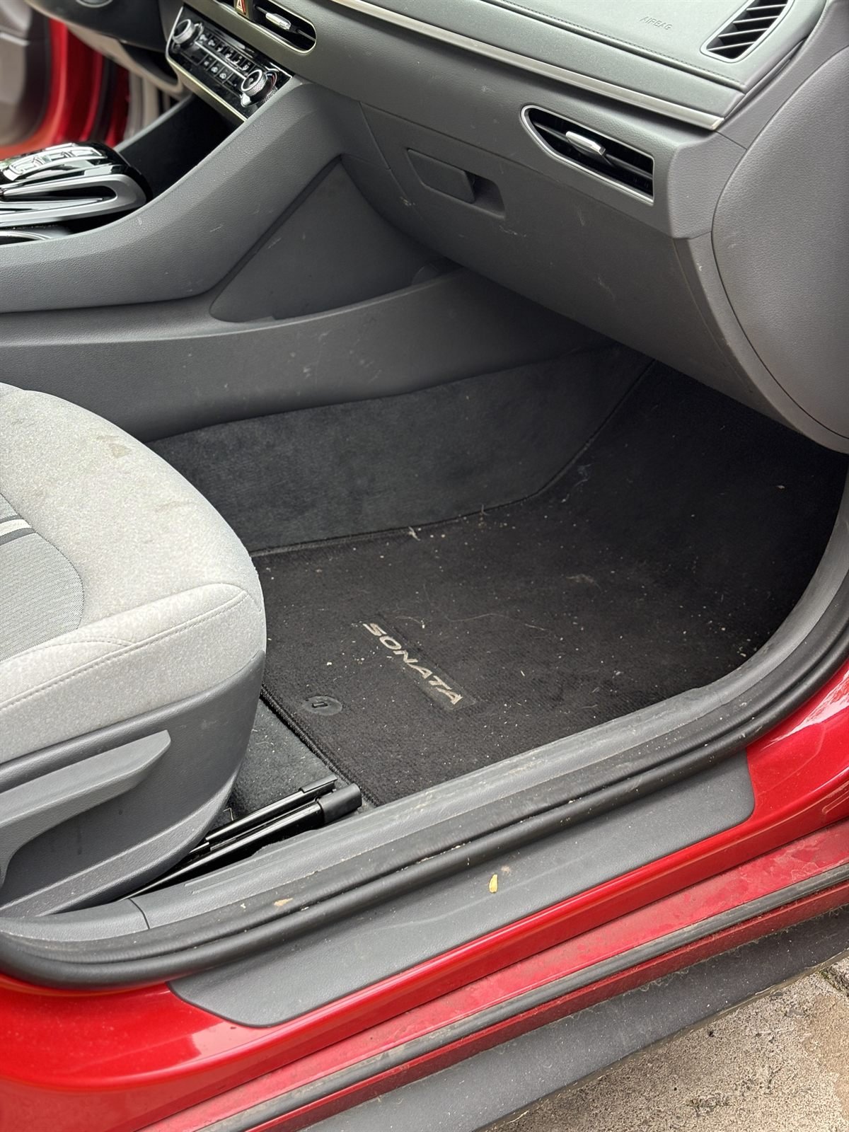 Before detailing: dirty door sill and floor mat of a red car