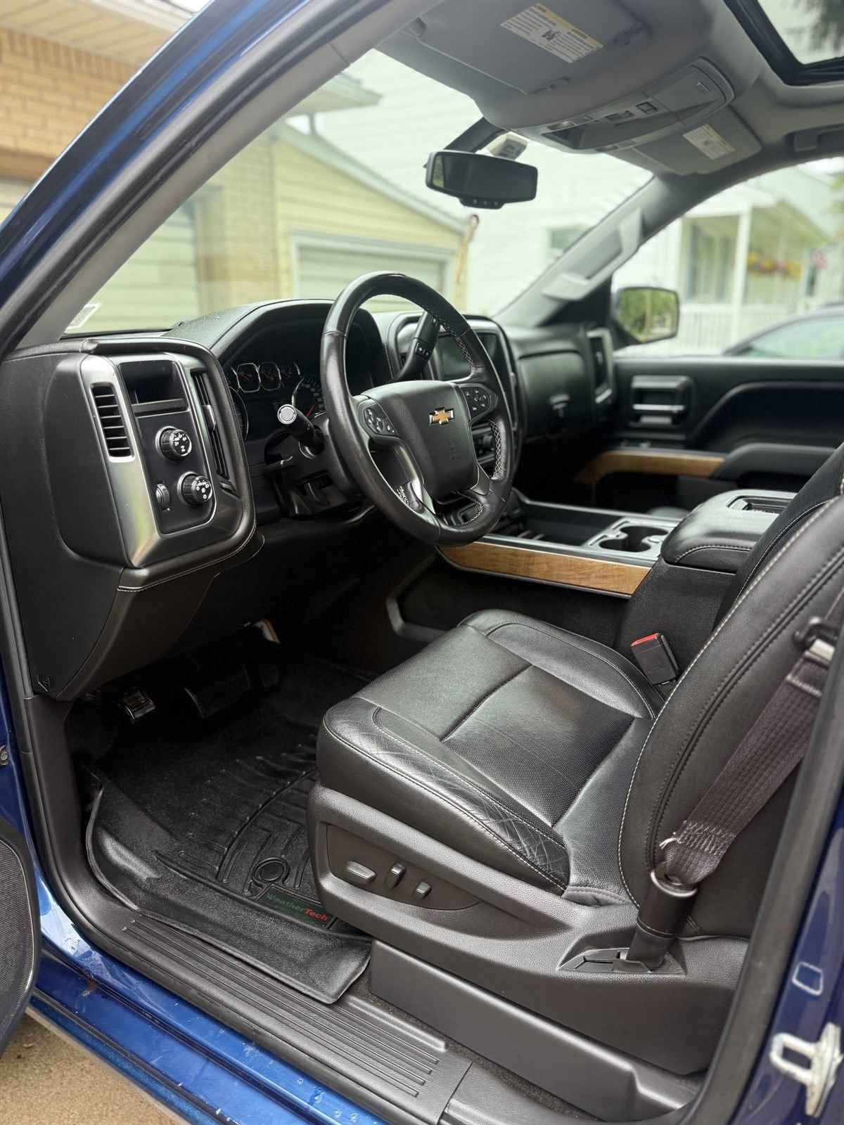 Detailed driver-side interior of a truck &mdash; black leather seat, dash and console