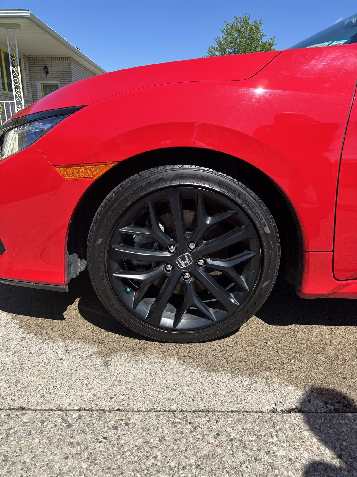 Glossy red sedan with black wheels after an exterior detail