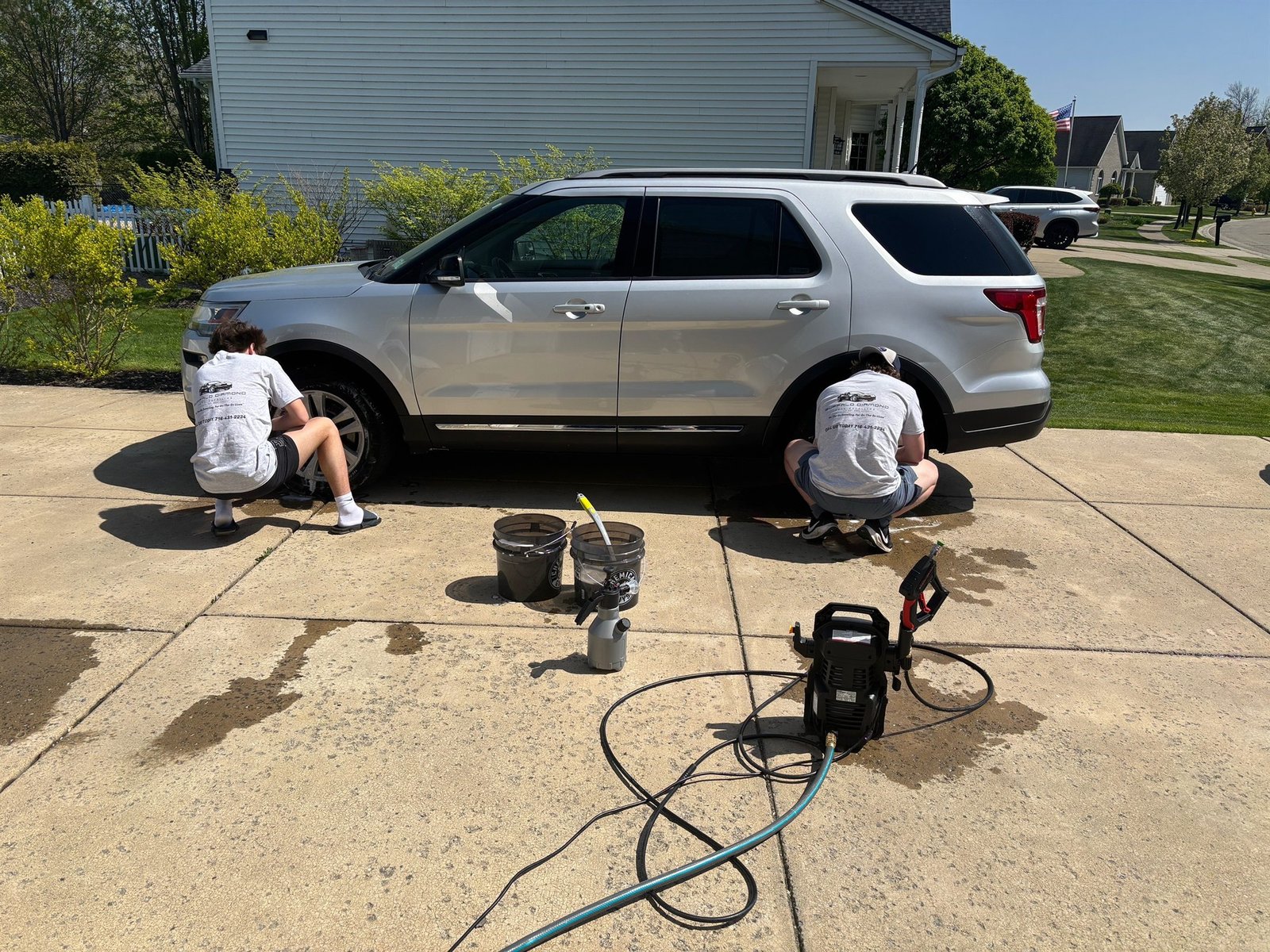 Quincy and Luca of Buffalo Diamond Detailing hand-washing a silver SUV in a sunny Buffalo, NY driveway